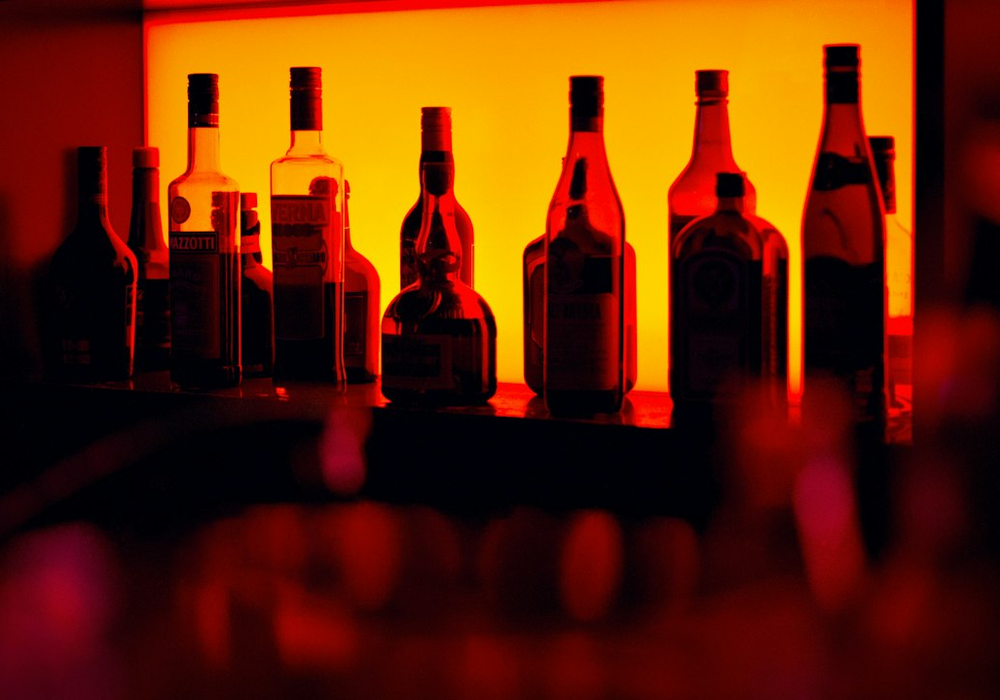 The main bar counter at PowerupDash with a backlit bottle shelf and stools along the rail