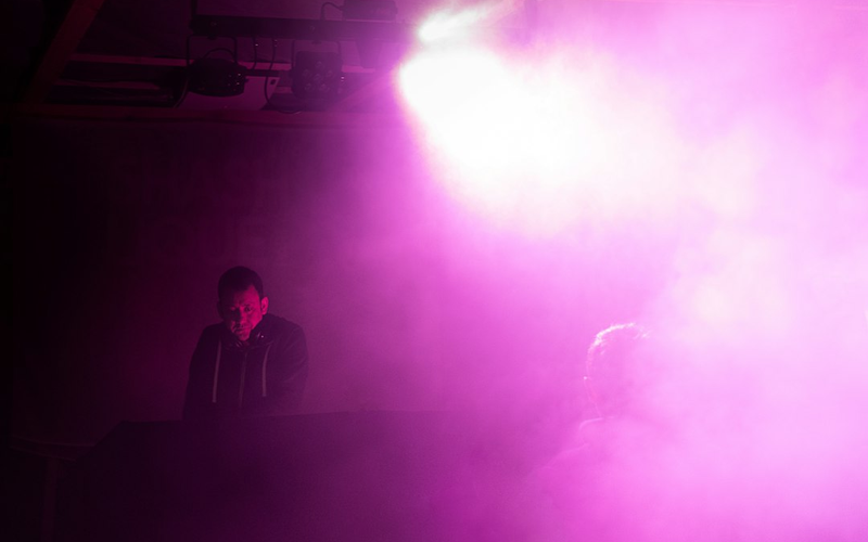 DJ playing to a packed dance floor under magenta stage lighting